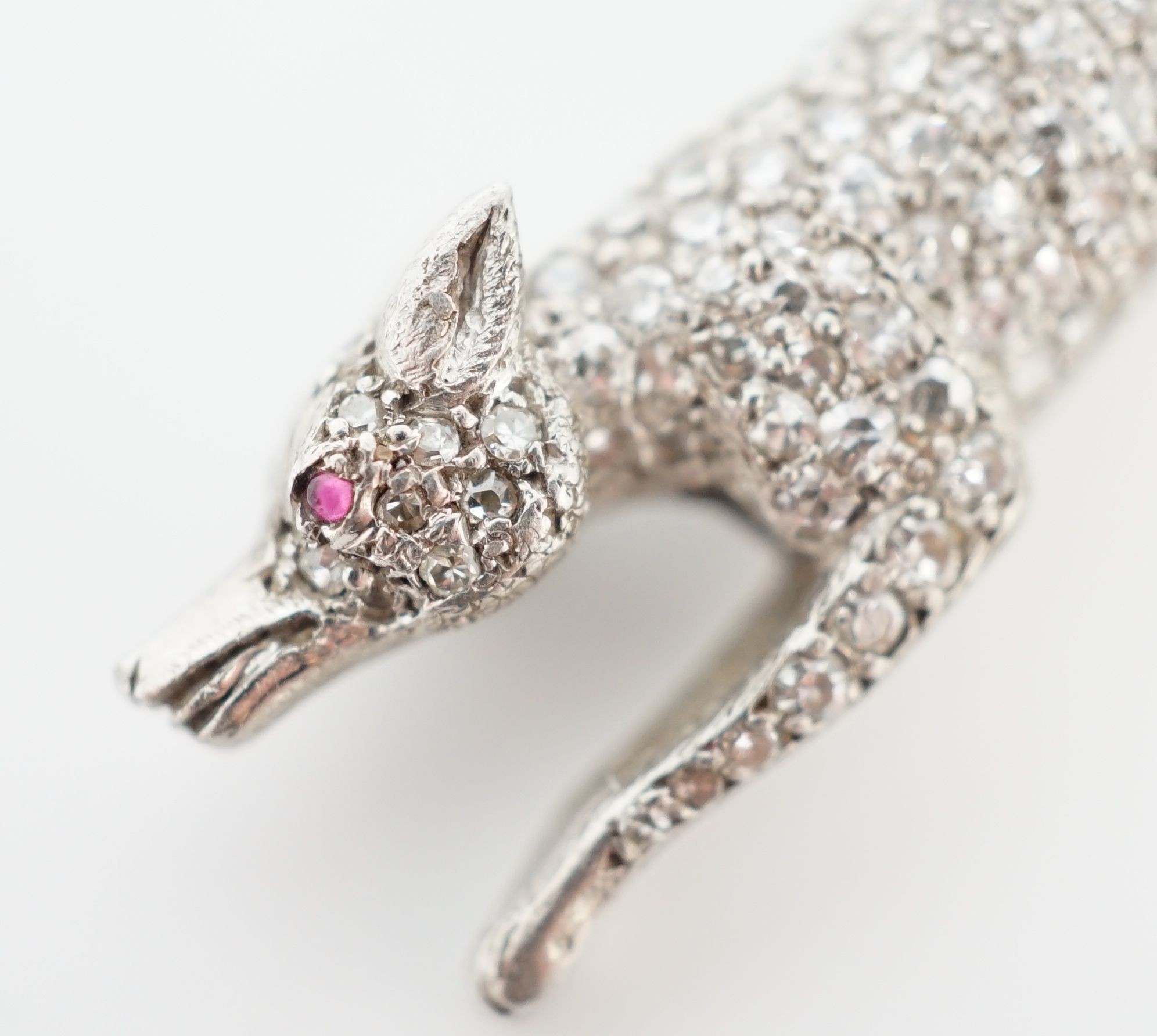 A Victorian style white gold, diamond encrusted and cabochon garnet set brooch, modelled as a running fox